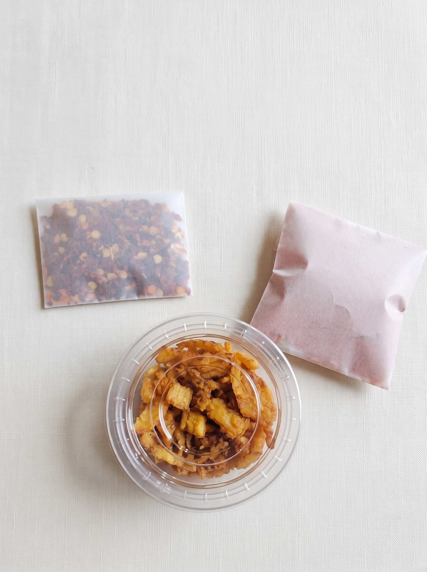 The chili sachet, spice sachet and fried-onion container laid out together