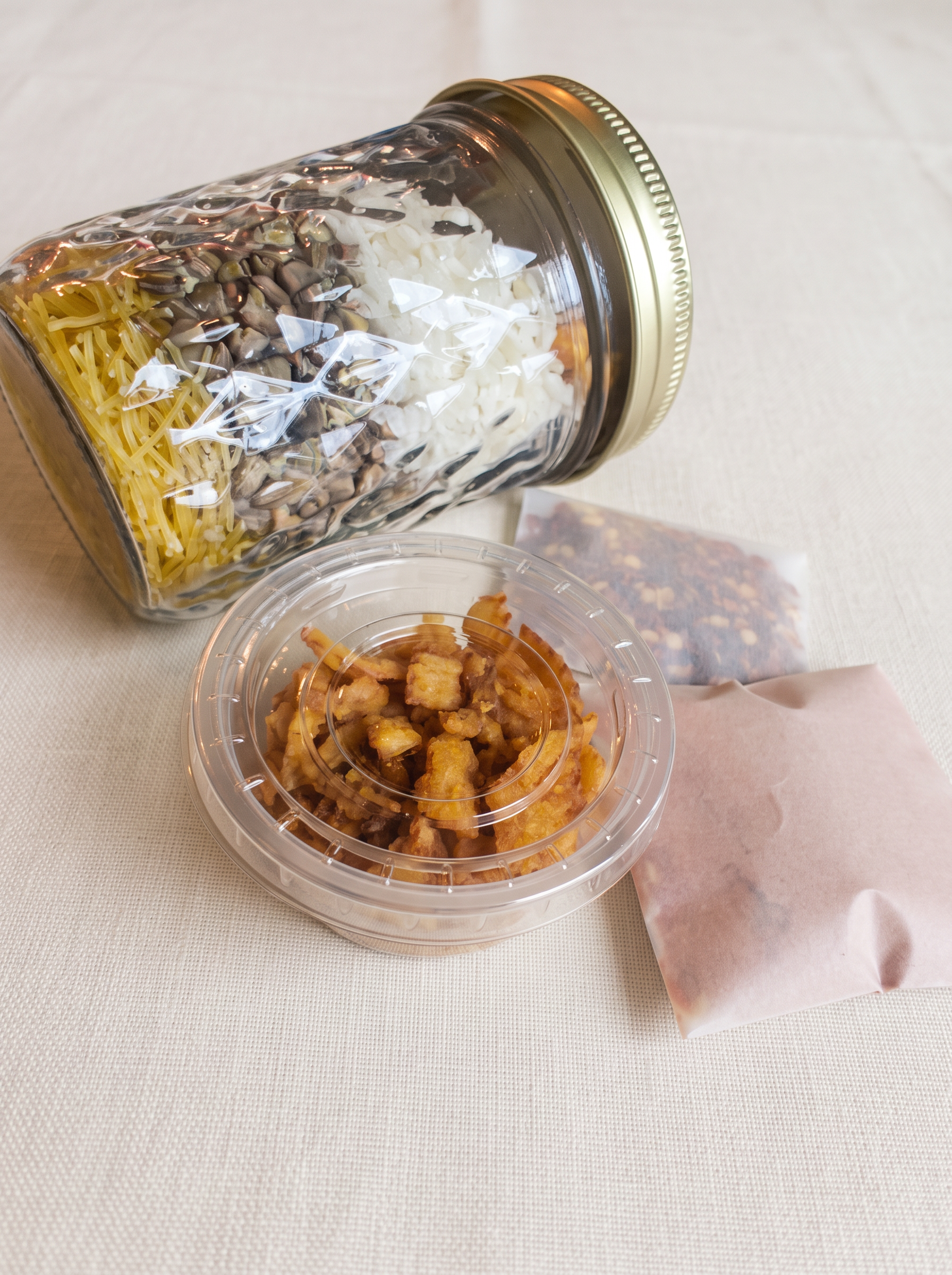 The layered jar resting on its side beside the fried-onion container and the spice and chili sachets